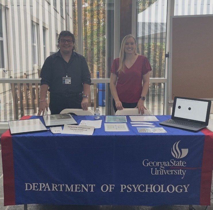 Elizabeth and a colleague at a Georgia State University Department of Psychology outreach table with research materials and a laptop task